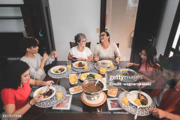 family having lunch at dining table served with feijoada, typical brazilian black bean stew - feijoada stock pictures, royalty-free photos & images