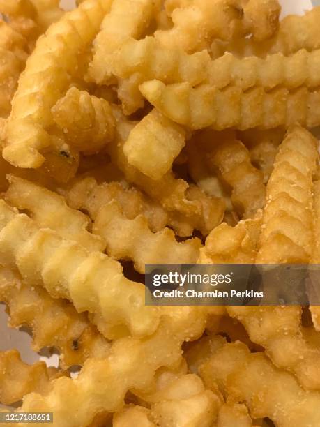 closeup of crinkle cut french fries, fried potato chips, take out meal at home during lockdown - scalloped stock pictures, royalty-free photos & images