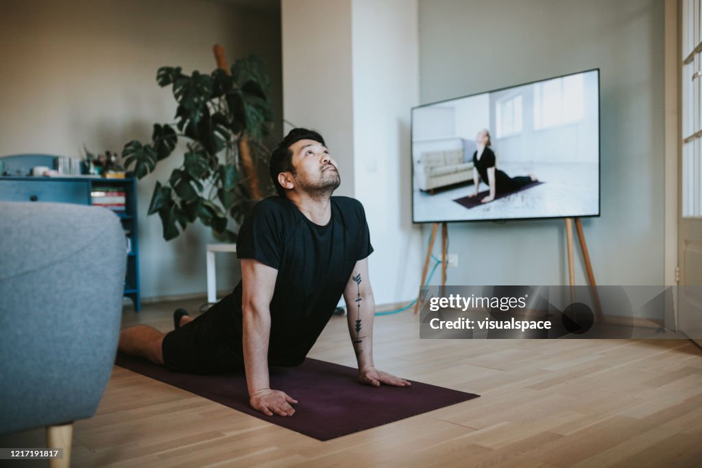 Hombre japonés tomando clases de yoga en línea durante el encierro en aislamiento