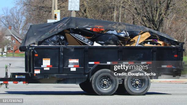cargo trailer being pulled with garbage and debris - müllcontainer stock-fotos und bilder
