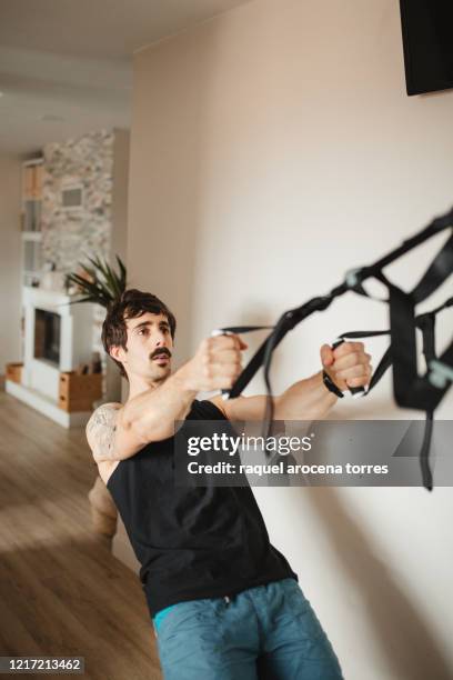 adult man practicing suspension training at modern home - suspension training stock pictures, royalty-free photos & images