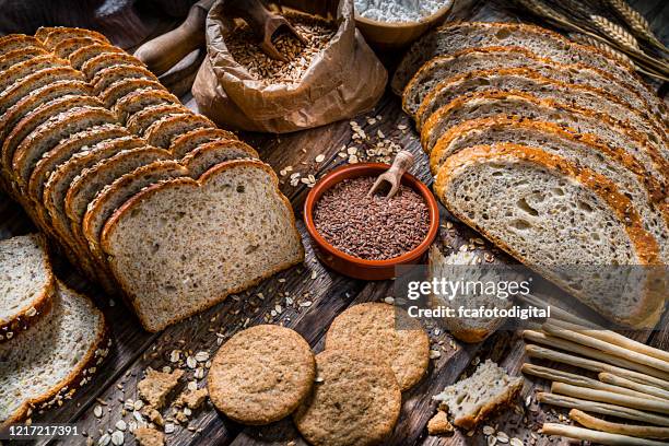healthy food: wholegrain bread with seeds and cereals on rustic kitchen table - rye bread stock pictures, royalty-free photos & images