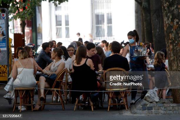 Waiter wearing a face mask serves clients while people eat and have drinks on the terrace of the cafe-restaurant in Paris on June 2 as cafes and...
