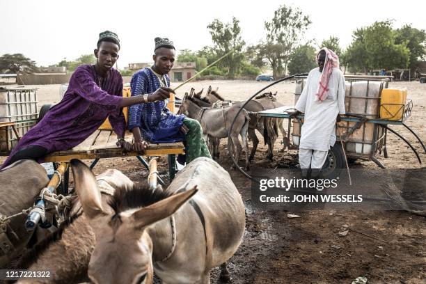 Fulani herders fill up their water tanks to take back to their camp at a unofficial herders market in Barkedji on May 29, 2020. Access to water comes...