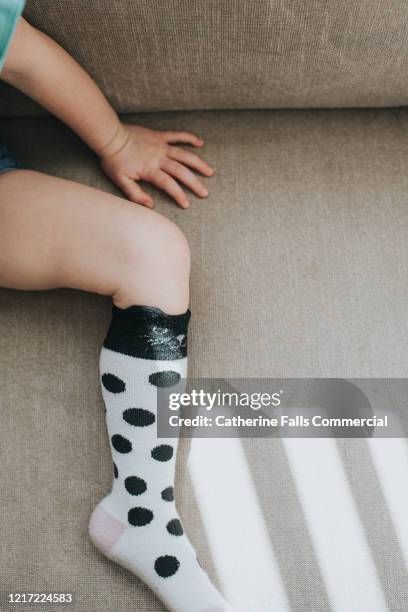 little foot wearing spotty knee sock - thigh stock photos et images de collection