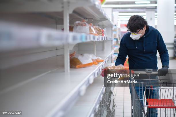 man's hands in protective gloves searching bread on empty shelves in a groceries store - covid 19 food stock pictures, royalty-free photos & images