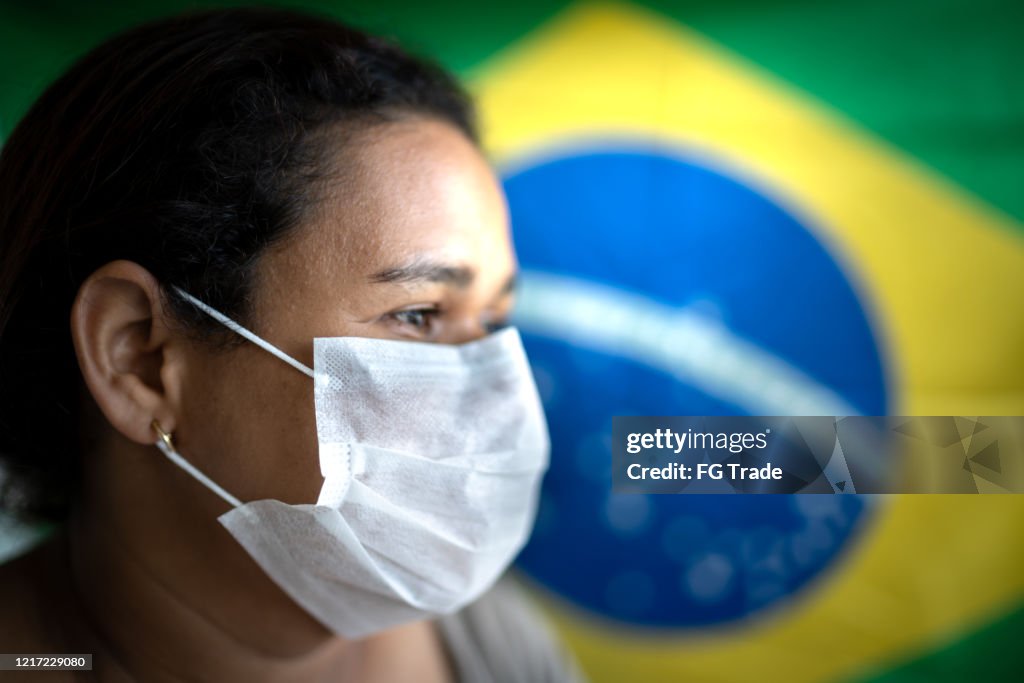 Frau mit Gesichtsmaske und brasilianischer Flagge im Hintergrund