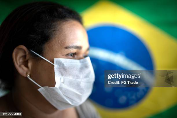 woman with face mask and brazilian flag on background - brazil covid stock pictures, royalty-free photos & images