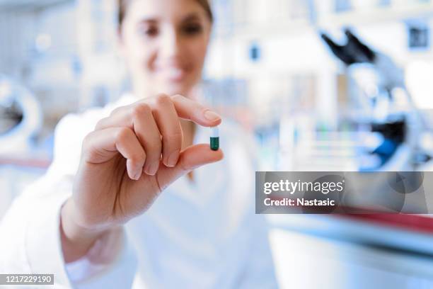 medicine doctor holding a color capsule pill in hand with white glove in laboratory - antibiotic pills stock pictures, royalty-free photos & images