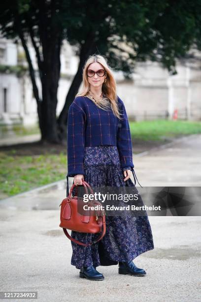 Charlotte Groeneveld wears sunglasses, a blue checked pullover, a blue floral print skirt, a burgundy leather Chloe bag, leather boots, outside...