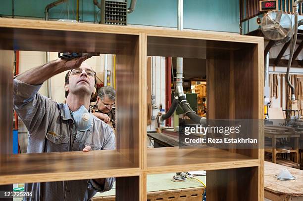 man fills holes in wood surface - mobilio foto e immagini stock