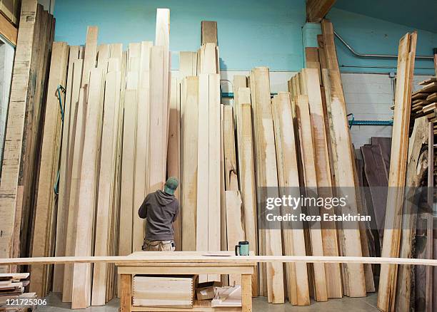 man selects wood from racks - woodwork stock pictures, royalty-free photos & images