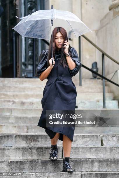 Guest wears a black long dress with leather puff sleeves, shoes with metallic tip, outside Chloe, during Paris Fashion Week - Womenswear Fall/Winter...