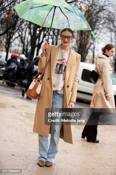Model Fran Summers wears a impressionist painting-style umbrella, oversized glasses, camel coat, Balloon Bag Ecru/Tan white bucket Loewe bag, Wet Hot...