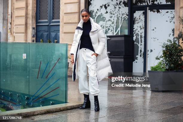 Model Karly Loyce wears a white puffer down jacket, black top, white cargo pants, and black booties after the Atlein show during Paris Fashion Week...