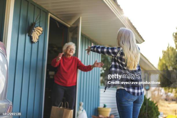 mature adult female delivering groceries to senior adult female and social distancing due to infectious virus outbreak pandemic - sharing stock pictures, royalty-free photos & images