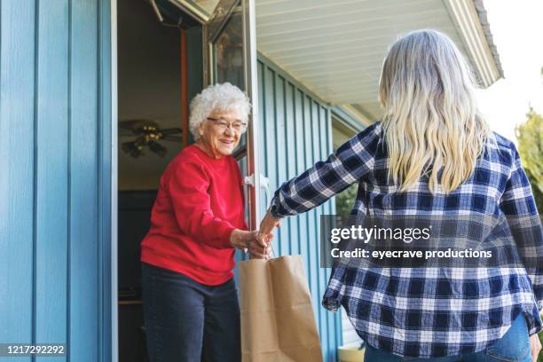 reife erwachsene frau liefert lebensmittel für ältere erwachsene weibliche und soziale entfernung aufgrund infektiöser virus ausbruch pandemie - meals on wheels stock-fotos und bilder