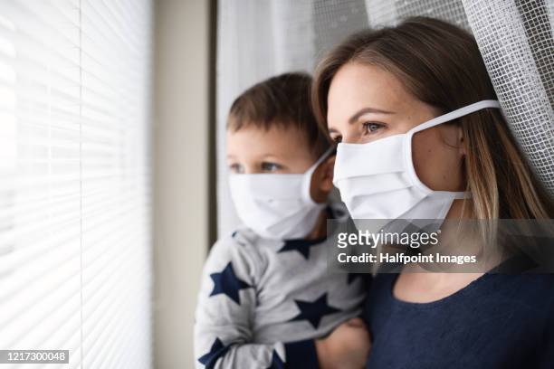 mother and small son with face mask indoors at home, quarantine concept. - pandemic illness photos et images de collection