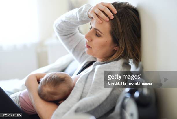 tired mother nursing baby daughter indoors at home, resting on bed. - dia bildbanksfoton och bilder