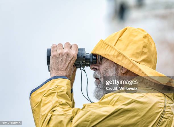 lighthouse keeper looking through binoculars close-up - rain hat stock pictures, royalty-free photos & images