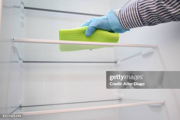 person with protective plastic gloves cleaning inside the fridge with a ballot - réfrigérateur fermé photos et images de collection