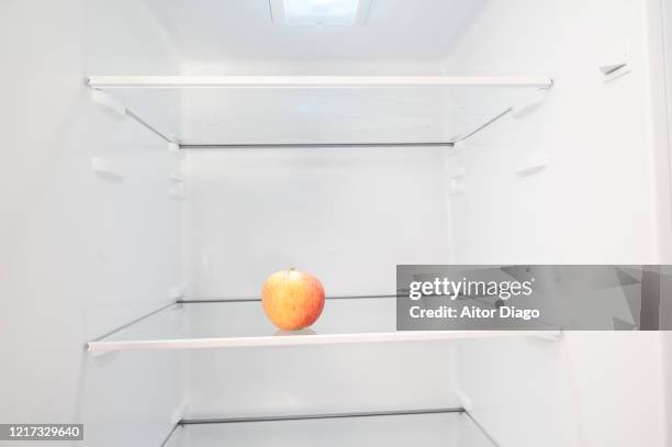 there is only one apple in the refrigerator. - kühlschrank leer stock-fotos und bilder