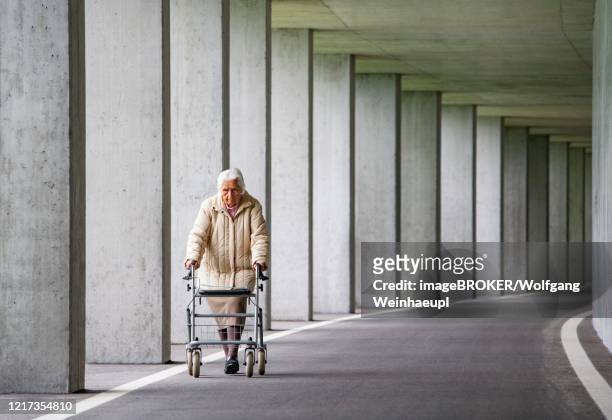 senior citizen with walker walks in an underpass, austria - old arm stock-fotos und bilder