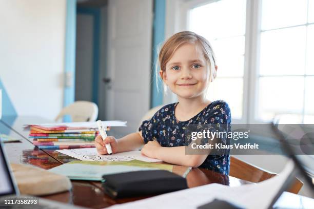 portrait confident girl doing homework at dining table - young girls homework stockfoto's en -beelden