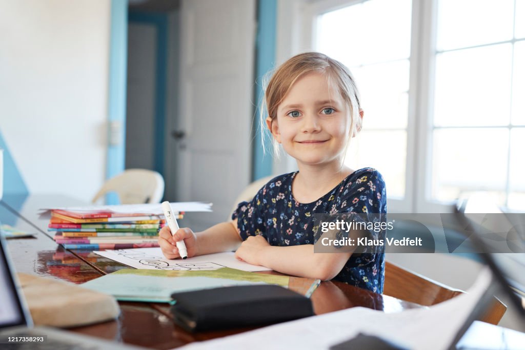 Portrait confident girl doing homework at dining table