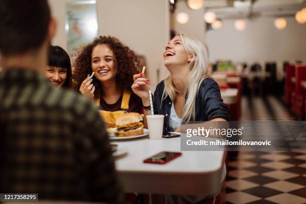 condividere cibo e barzellette - girls laughing eating sandwich foto e immagini stock
