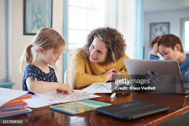 mother homeschooling daughter and son at table - spelling stock photos et images de collection