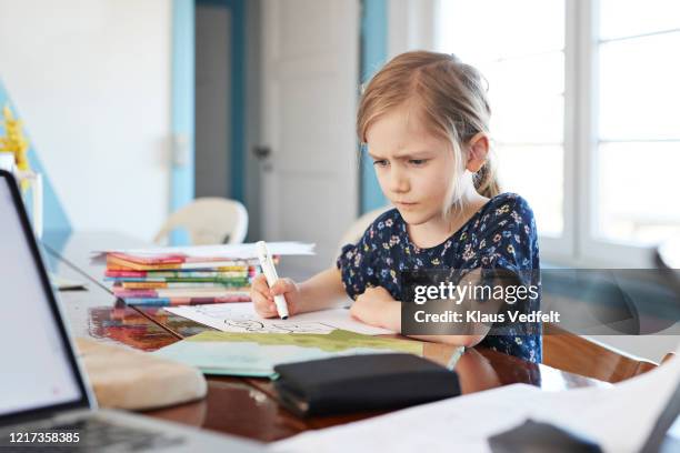 serious girl doing homework at dining table - confused writing stock-fotos und bilder