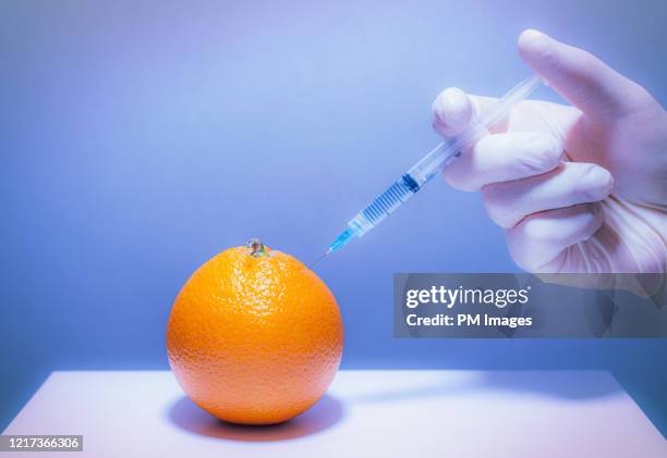 hand injecting orange with syringe - food contamination stock pictures, royalty-free photos & images