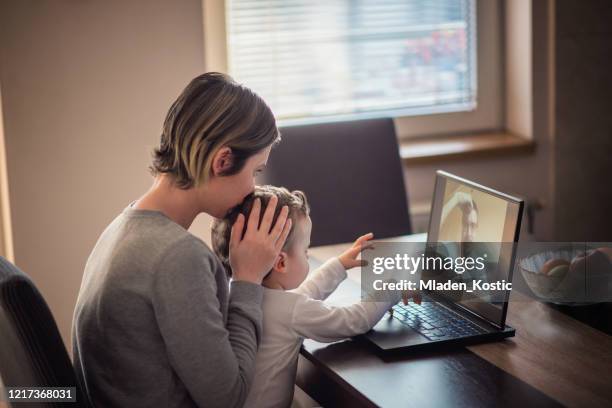 orolig mamma kysser småbarn huvud under hans videosamtal med separerade far - children divorce bildbanksfoton och bilder