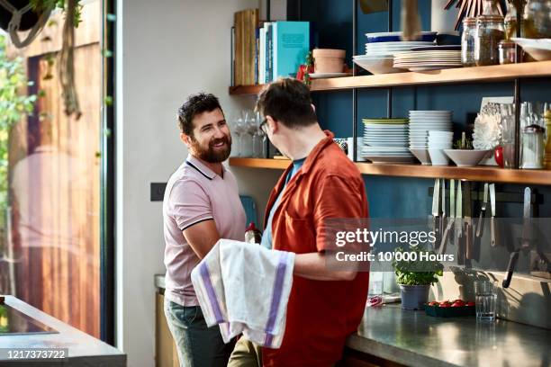 cheerful male couple washing up together in kitchen - couples showering stock-fotos und bilder