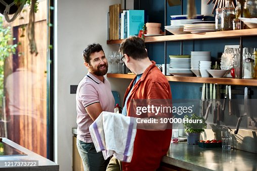 Cheerful male couple washing up together in kitchen Cheerful male couple washing up together in kitchen