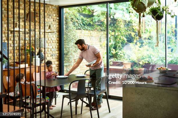 father setting dining table with young children - mettre la table photos et images de collection