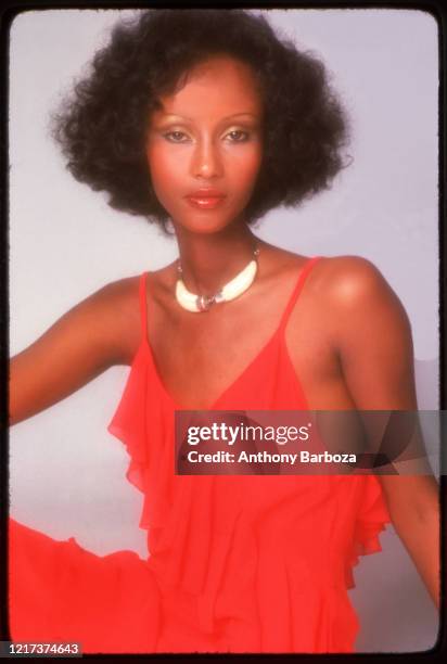 Portrait of Somali-born American fashion model Iman, in a red dress, as she poses against a white background, 1975.