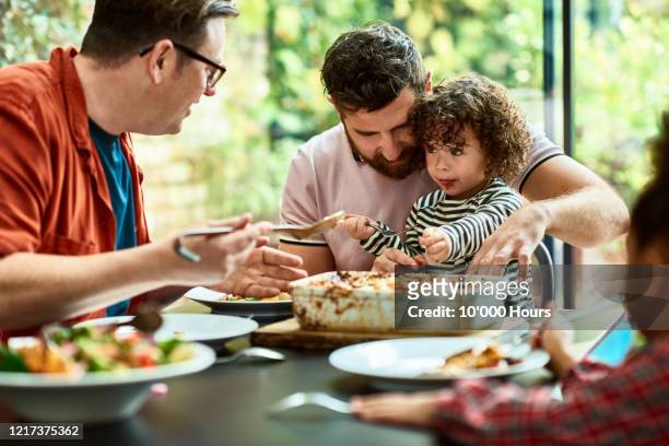 messy toddler eating vegan lunch with adopted family - repas photos et images de collection