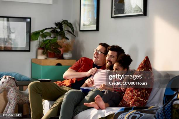 fathers with adopted daughter laughing together on sofa - family in front of tv stock pictures, royalty-free photos & images