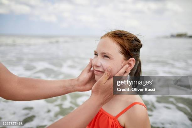 portrait of girl looking at her mother by the sea - young girl swimsuit stock-fotos und bilder