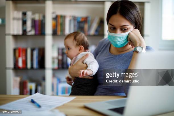 worried mother with face protective mask working from home - unemployment benefits stock pictures, royalty-free photos & images