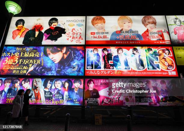 Women walk past signage in Tokyo's Kabukicho adult entertainment area in the Shinjuku district on April 07, 2020 in Tokyo, Japan. Japan's Prime...