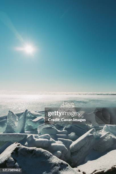 large flat pieces of ice piled up along the shore of a lake in winter. - broken glass pieces stock pictures, royalty-free photos & images