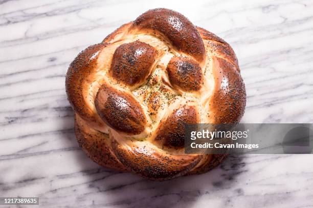 braided round challah bread loaf with poppy seeds - geflochtenes brot stock-fotos und bilder