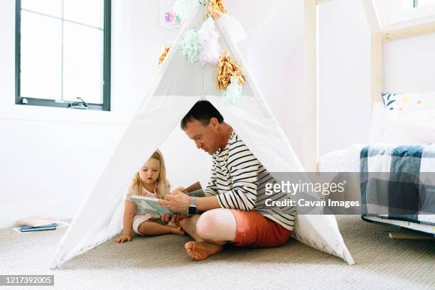 closeup portrait of a dad and child reading together in a child's room - kids fort stock pictures, royalty-free photos & images