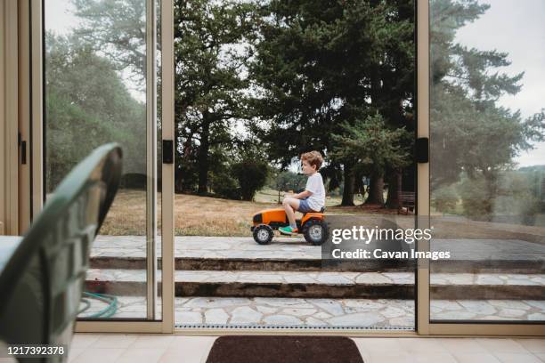 view through doors of boy on toy tractor - toy tractors stock pictures, royalty-free photos & images
