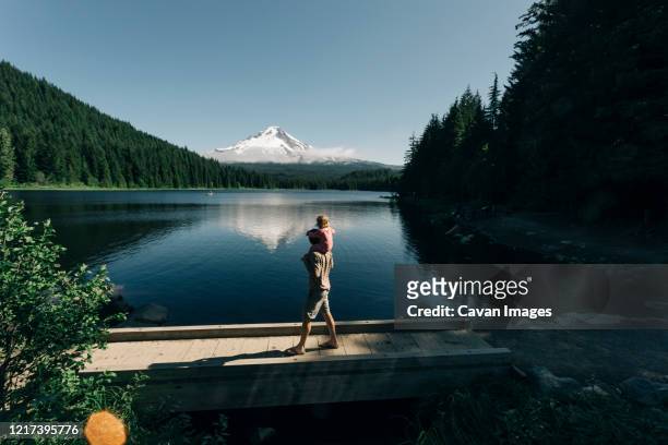 a father carries his daughter on his shoulders at trillium lake, or. - oregon wilderness stock pictures, royalty-free photos & images