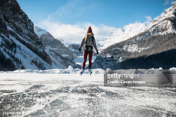 woman ice skating on frozen lake at lake louse in banff national park - lake louise ストックフォトと画像