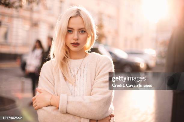 portrait of young woman with arms crossed standing on city street - bright blue eyes stock pictures, royalty-free photos & images